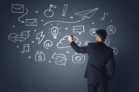 Young businessman in black suit standing in front of white mixed media icons