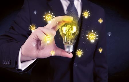 A creative businessman has a bright idea concept with office worker holding light bulb in foreground.