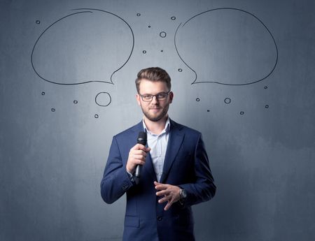 Businessman speaking into microphone with speech bubbles over his head