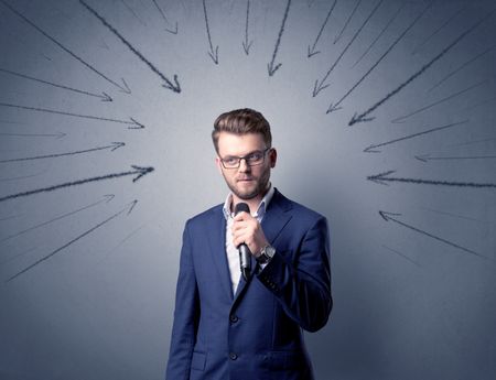 Businessman speaking into microphone with arrows pointing towards his head