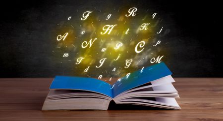 Glowing yellow alphabet letters coming out of an open book 