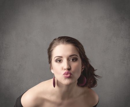 pretty-young-teenage-girl-standing-front-657536566 A pretty young teenage girl standing in front of a grey clear empty urban wall background concept while making funny faces.
