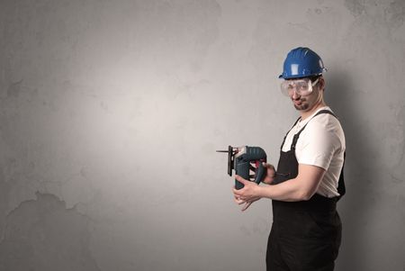 Craftsman standing in front of an empty wall with tool in his hand.