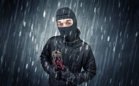 Burglar in action in black clothes with rainy concept. 