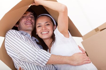 Happy couple with cardboard boxes moving to a new house