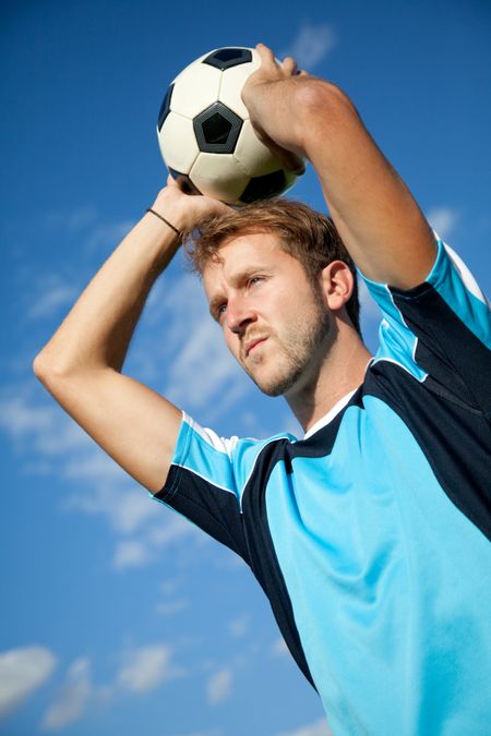 Footballer holding the ball and doing a throw in outdoors