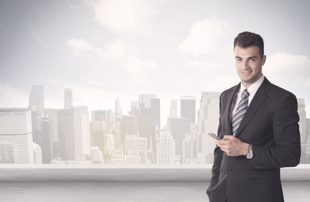 A young adult businessman standing in front of city landscape with skyscraper buildings and clouds concept