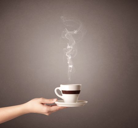 Young female hand holding steaming coffee cup 