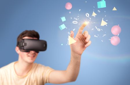 Young impressed man wearing virtual reality goggles with geometric shapes around his hand