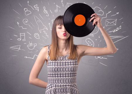 Young lady holding vinyl record on a grey background with mixed scribbles behind her