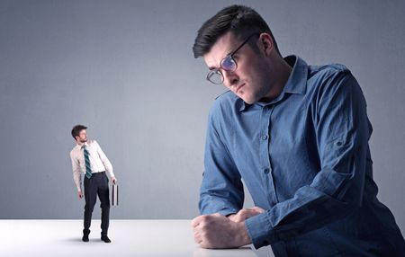 Young professional businessman being angry with an other miniature businessman 