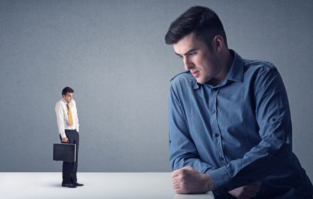 Young professional businessman being angry with an other miniature businessman