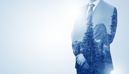 Young businessman standing and meditate with trees on the background 