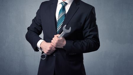 Young, handsome, cute businessman holding tool with grey background