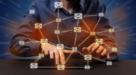 Businessman in suit typing with connected mail icons around 