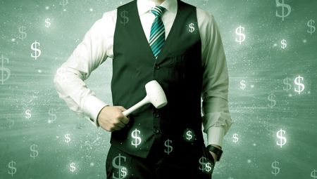 Handsome businessman holding tool with dollar symbols around and with green background