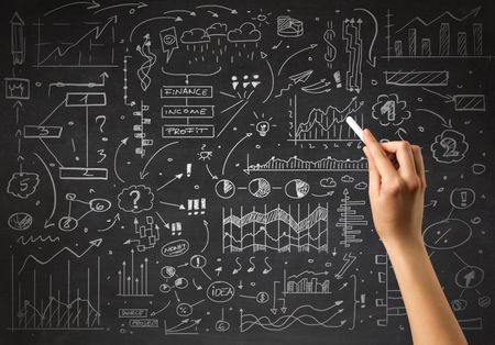 Female hand holding white chalk in front of a blackboard with a business plan drawn on it