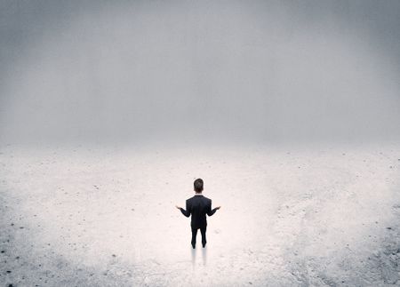 An adult elegant businessman standing in the middle of nowhere in empty grey concrete space background concept