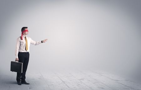 A young male business person in elegant dress standing with red blindfolds in a clear, empty space concept.