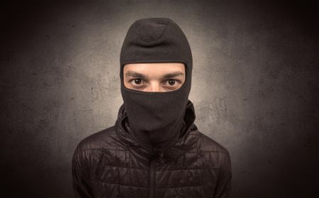 Burglar standing in black clothes and balaclava on his head.