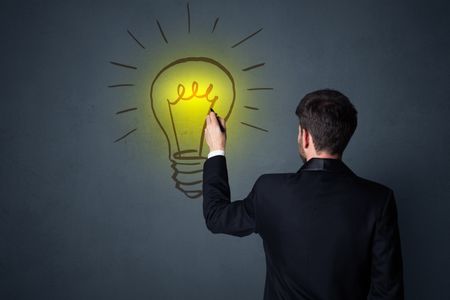 Young businessman in black suit standing in front of a drawn yellow lightbulb