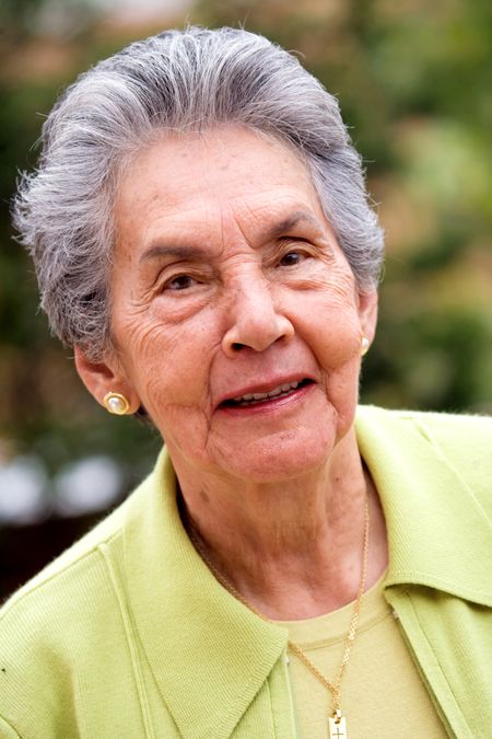 happy retired woman portrait smiling outdoors in green colours