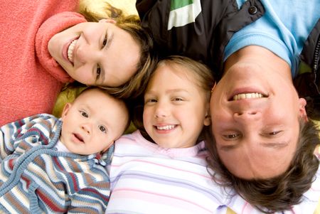 happy family portrait all smiling on the floor with heads together