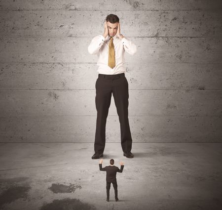 Huge angry business guy looking at small coworker concept on background