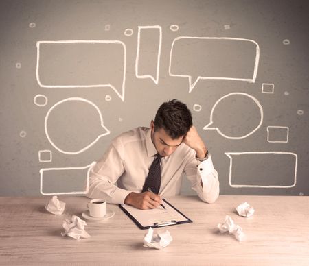 An intelligent elegant business person sitting at a desk and working with drawn empty text bubbles, boxes around him concept