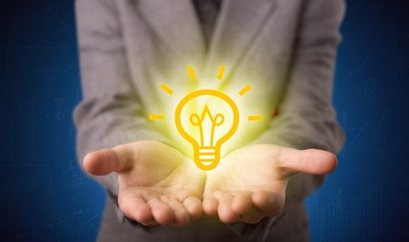A creative businessman has a great bright idea illustrated by holding a drawn light bulb in the hand concept