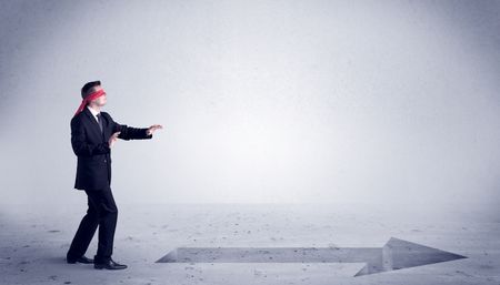 A confused blind salesman standing in front of a drawn arrow on the floor pointing in the right direction concept.