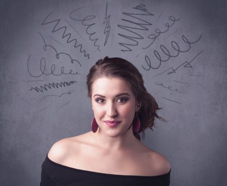 A cute female student making funny face expressions with pressure and problems in her head illustrated by drawn lines, marks and spirals on the urban wall background concept.