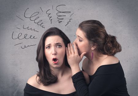 A cute teen caucasian girl telling secret things to her girlfriend dressed in black dress concept with drawn lines, curves, spirals on grey wall background.