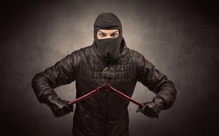 Burglar standing in black clothes and balaclava on his head.