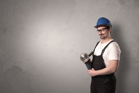 Craftsman standing in front of an empty wall with tool in his hand.