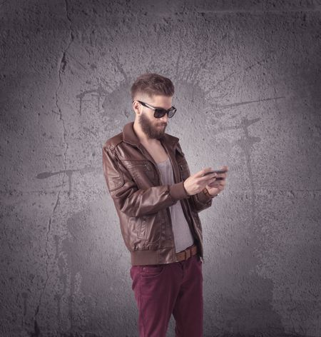 hipster-fashion-model-guy-casual-clothing-667144348 A hipster fashion model guy in casual clothing stnading with mobile phone in front of concrete urban wall background concept