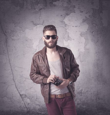 Funny vintage guy with long beard and stylish hair standing in front of urban concrete wall concept