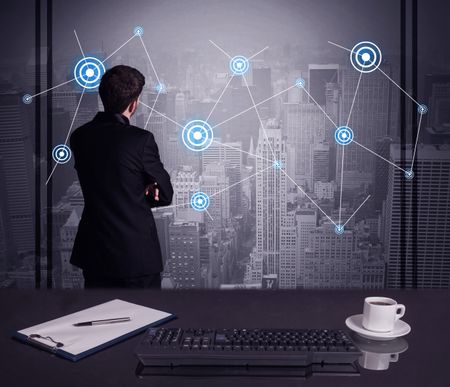 An elegant businessman connecting blue circle dots on urban city scape background concept at an office desk in a conference room