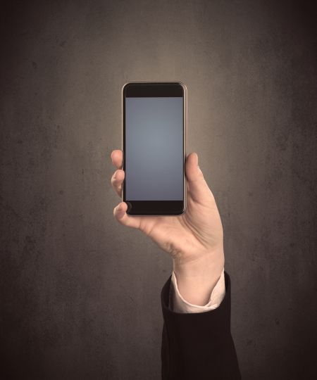 Caucasian hand in business suit holding a blank screen smartphone
