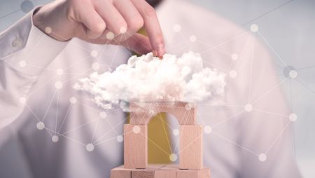 Young handsome businessman using wooden building blocks behind cloud concept 
