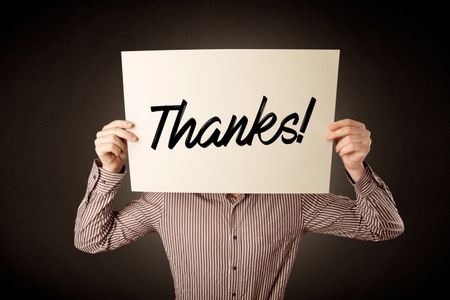 Young businessman hiding behind an expression of gratitude drawn on paper