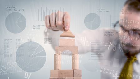 Young handsome businessman using wooden building blocks with data and numbers around him