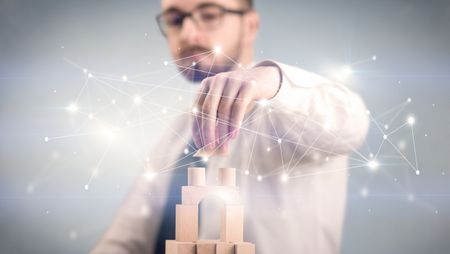 Young handsome businessman using wooden building blocks with interconnected lines and dots around him