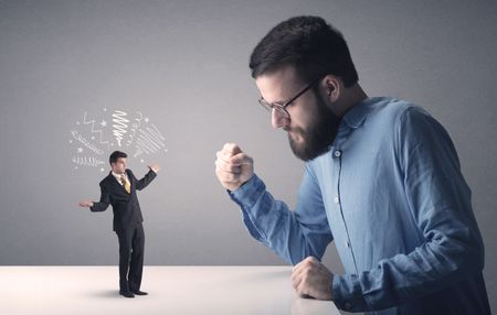 Young professional businessman being angry with an other miniature businessman who has scribbles above his head
