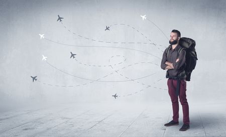 Handsome young man standing with a backpack on his back and little planes in the background