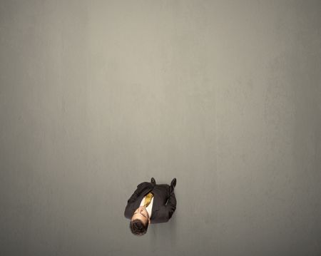 Young businessman contemplating a decision standing on a grey surface