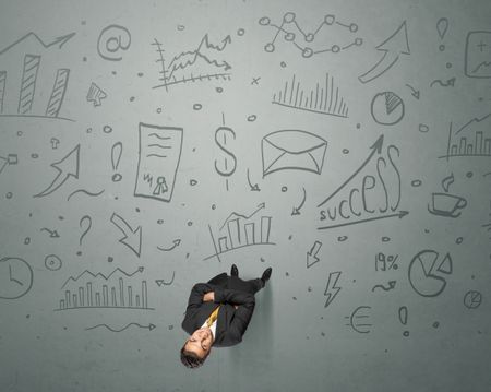 Young contemplating businessman stands in front of business graphics
