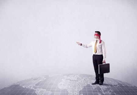 Young blindfolded businessman steps on a grey world map