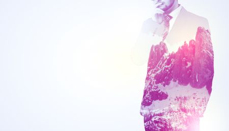  Young businessman in suit standing with sunny snowy mountain and trees graphic.