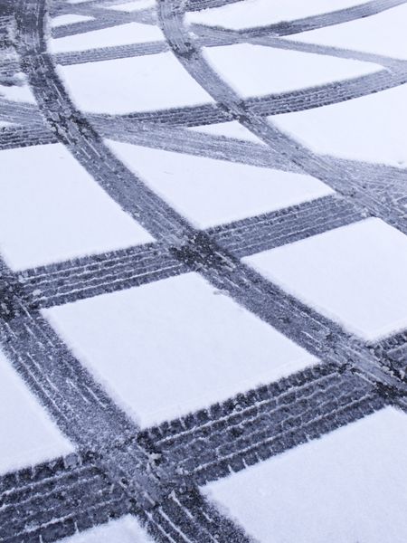 Winter at a glance -- crisscross pattern of tire tracks in snow on parking lot